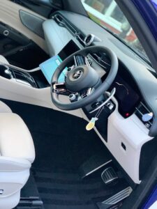 Interior of a modern car showcasing a sleek design with a black and white leather combination. Features a round steering wheel, a central console with touch controls, an electronic gear shift, and a keychain hanging from the ignition switch.