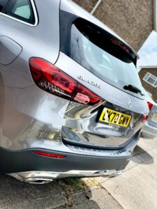 A silver Mercedes-Benz GLA 200 is parked on a residential street. The vehicle's license plate reads "LX70 GMV," and the rear of the car is prominently visible, showcasing its taillights and chrome accents. A brick building is partially visible in the background.